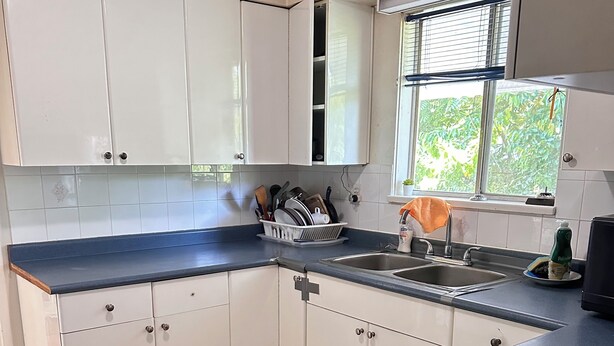 A kitchen with white cabinets, a blue countertop, and a window with blinds. - Spacious 8-bedroom house in gorgeous Richmond with AC (Richmond)