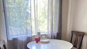 A round dining table with two chairs, a window with patterned curtains, and a view of trees outside. - Spacious 8-bedroom house in gorgeous Richmond with AC (Richmond)