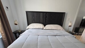 En seng med en quiltet madras, en mørk sengegavl og to sengeborde med lamper.