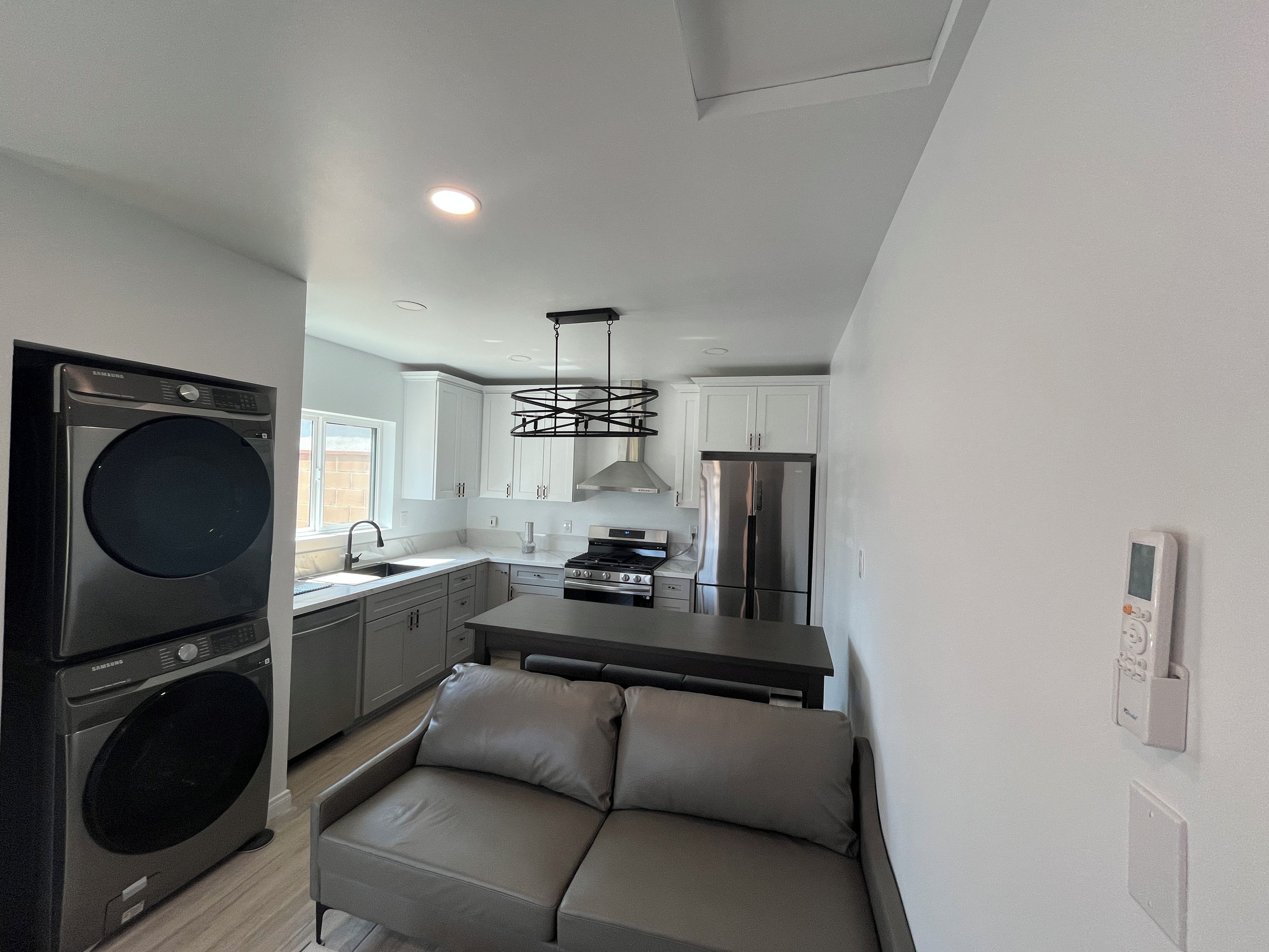 A compact kitchen with a built-in washer, a dining area with a bench, and a modern pendant light.