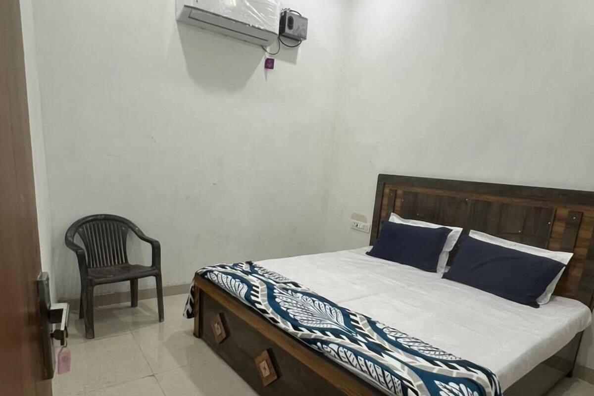 Un dormitorio con cama, una silla, un equipo de aire acondicionado y una puerta.