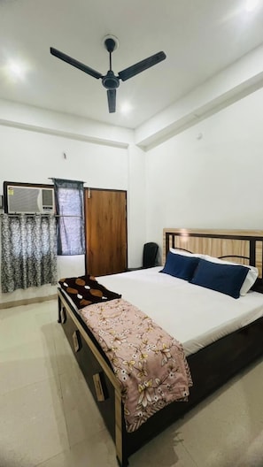 A bedroom with a bed, a ceiling fan, a wardrobe, and an air conditioning unit. - Brij Nandan Place (Mathura)