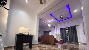 A spacious living area with a modern ceiling design, a sofa, and a desk with a laptop. - Miky Hillside Lodge (Sunyani)