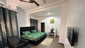 A modern bedroom with a large bed, a desk, and a TV. - Miky Hillside Lodge (Sunyani)