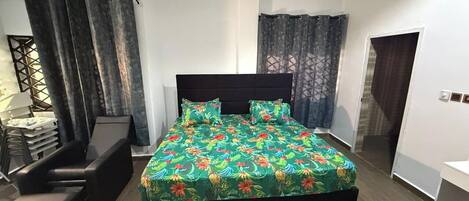 Quarto moderno com cama grande, escrivaninha e cadeira.