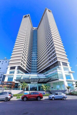 A modern high-rise hotel with a distinctive zigzag design, featuring a glass facade and a covered entrance area.