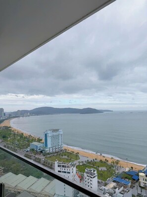 A coastal cityscape with a beach, a large hotel, and distant mountains.
