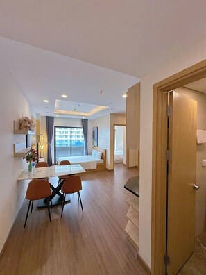 A modern hotel room with a dining area, a bed, and a view of the city.