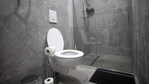Et moderne badeværelse med toilet, bruser og et brusekabine med glas.