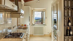 Uma cozinha com fogão a gás, radiador branco e uma estante para vinhos com garrafas.