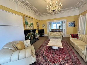 A spacious living room with a chandelier, a large red patterned rug, and a television. - Stunning exclusive apartment in Clifton, Bristol, UK 2 bedrooms 6 beds 2 baths (Bristol)