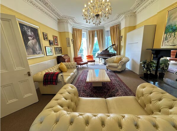 A luxurious living room with a grand piano, plush sofas, and a chandelier. - Stunning exclusive apartment in Clifton, Bristol, UK 2 bedrooms 6 beds 2 baths (Bristol)