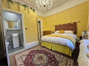 A bedroom with a large bed, a chandelier, a bathroom with a mirror and sink, and a red and beige patterned rug. - Stunning exclusive apartment in Clifton, Bristol, UK 2 bedrooms 6 beds 2 baths (Bristol)