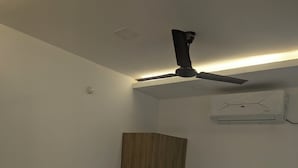 Een eenpersoonsbed met een houten hoofdbord, een plafondventilator en een airconditioning op de muur.