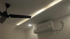 Een plafondventilator, een airconditioningsapparaat en een houten kast in een kamer.