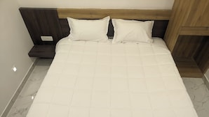 Een bed met een houten hoofdbord, twee witte kussens en een wit gebogen matras.
