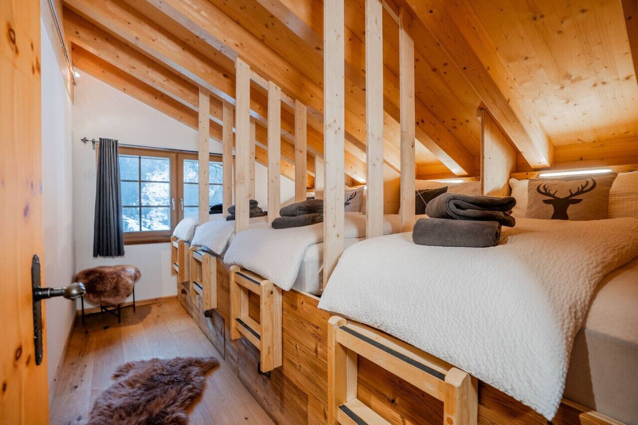 Een gezellig vakantiehuisje met houten balken, een bont tapijt en een raam met gordijnen.