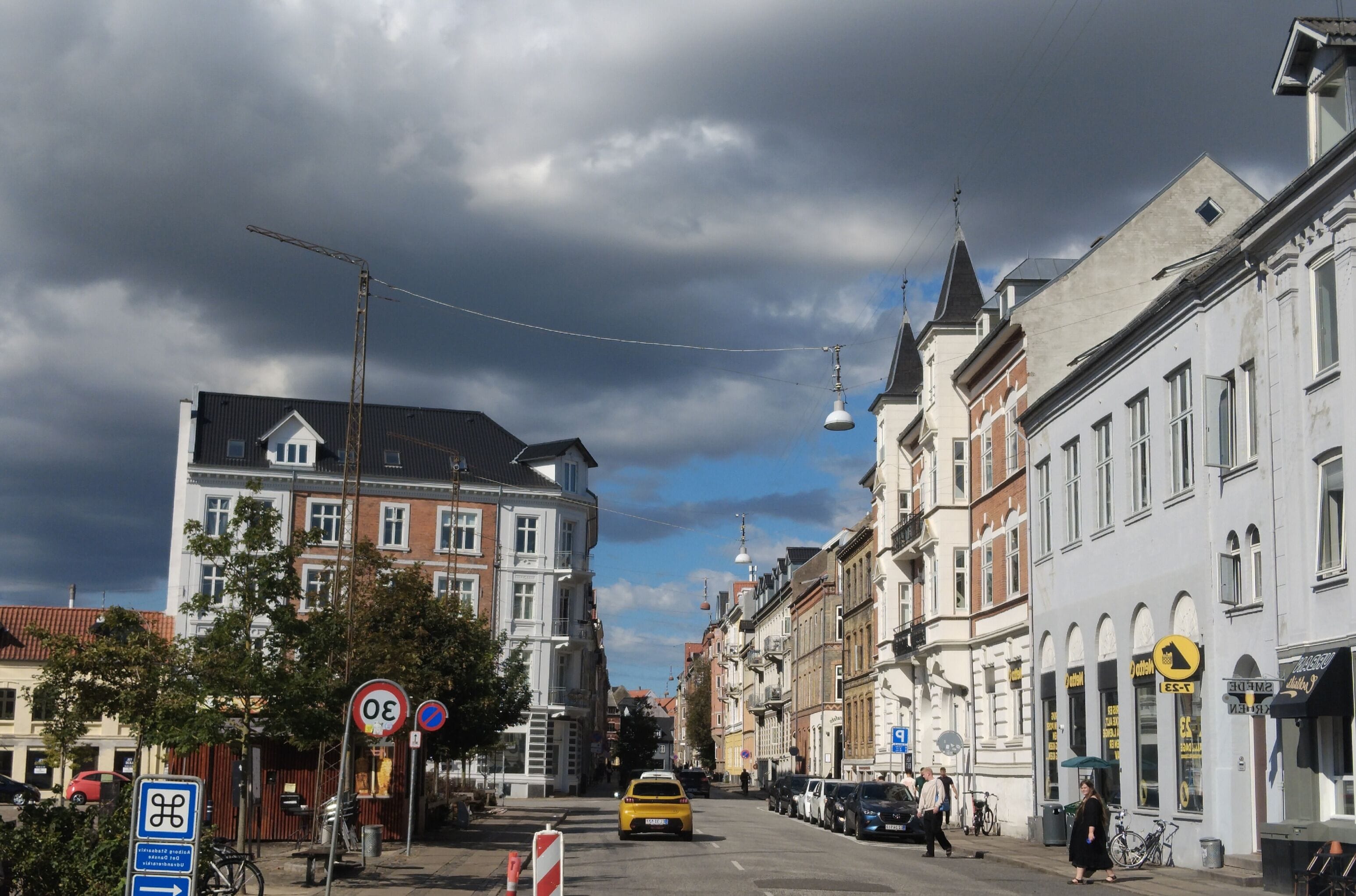 A street view with buildings, a yellow taxi, and a clear sky.