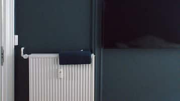 Una habitación con una pared azul oscuro, un radiador blanco y suelo de madera.