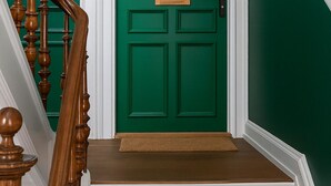 A staircase with wooden balusters leading to a green door with a handle and a nameplate. - Greenbrook Blue Suites (Aalborg)
