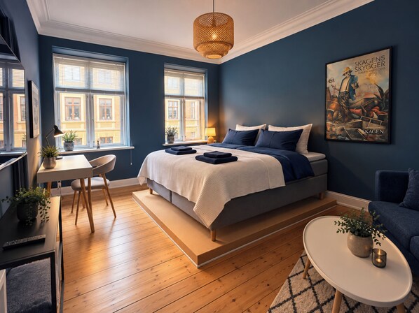 A bedroom with a bed, bedside tables, a desk, and a chair. - Greenbrook Blue Suites (Aalborg)