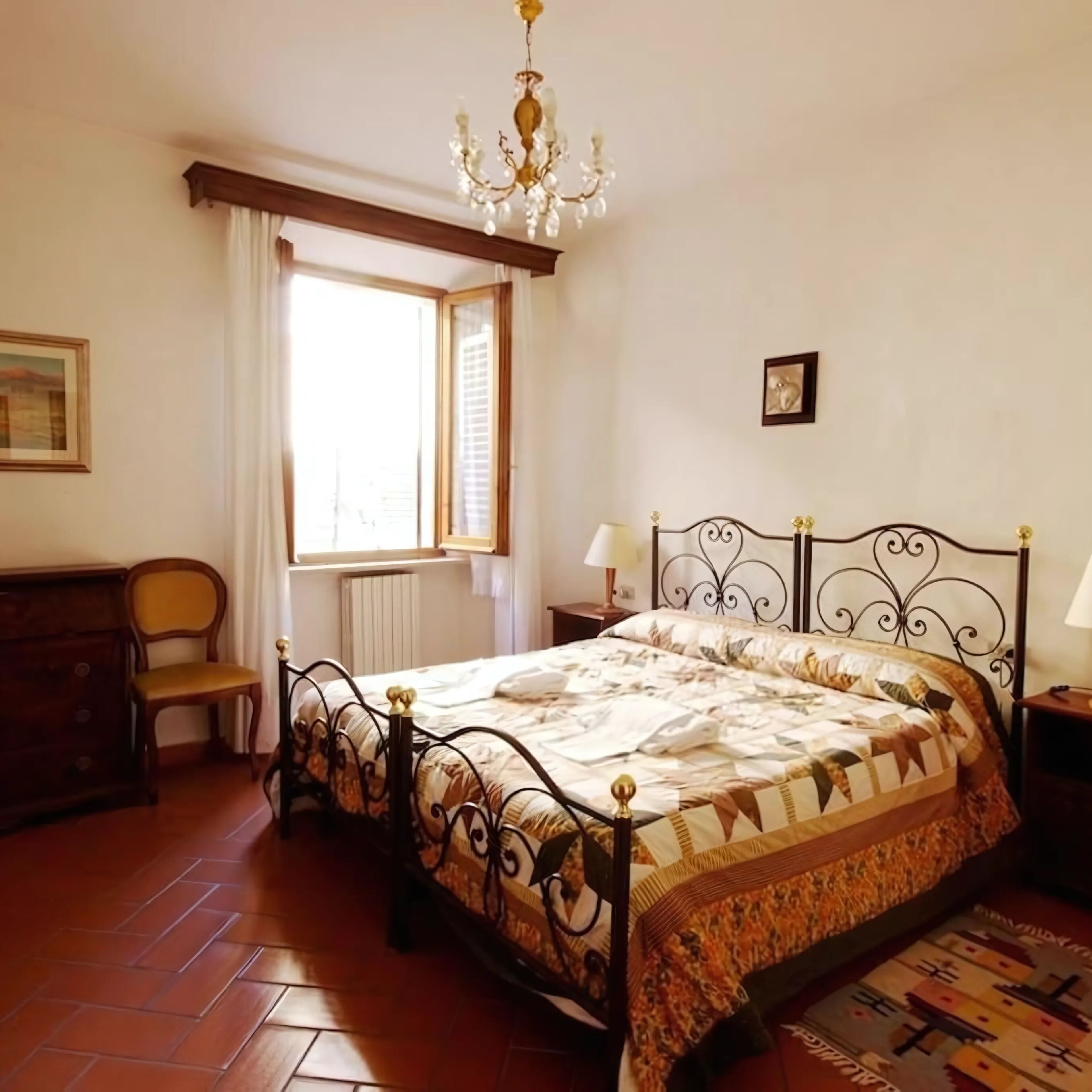 Une chambre à coucher comprenant un lit, une chaise, une commode, une fenêtre et un lustre.