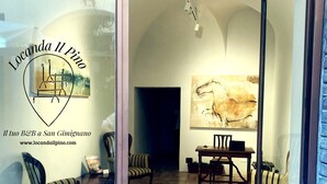 A cozy interior with a dining area, striped chairs, a rug, and a painting on the wall. - Locanda Il Pino (San Gimignano)