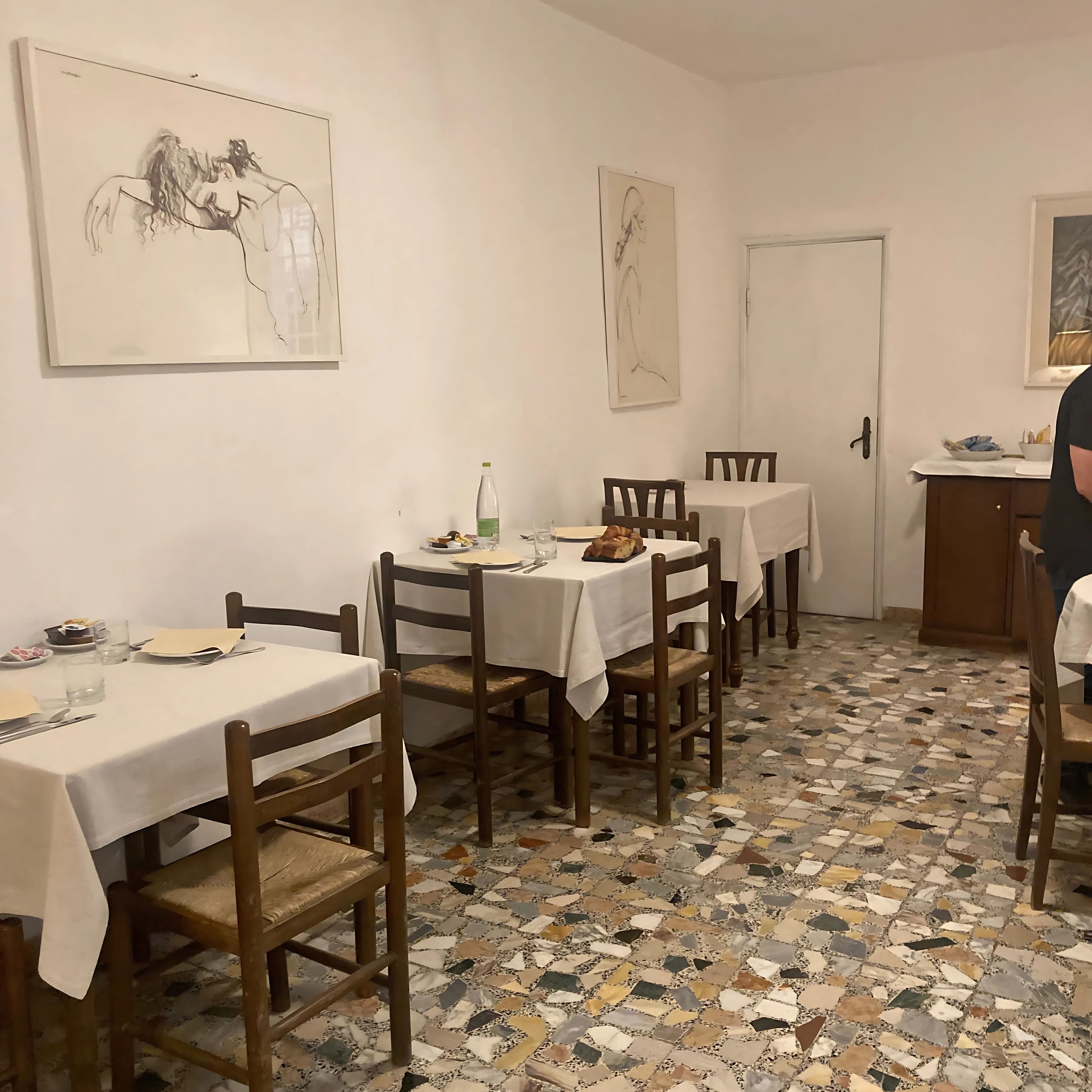 A dining area with multiple tables, chairs, and artwork on the walls.