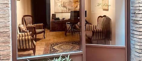 Un interior moderno con un gran ventanal, una zona de estar con sillas a rayas, un escritorio y una pared decorativa con un logo.