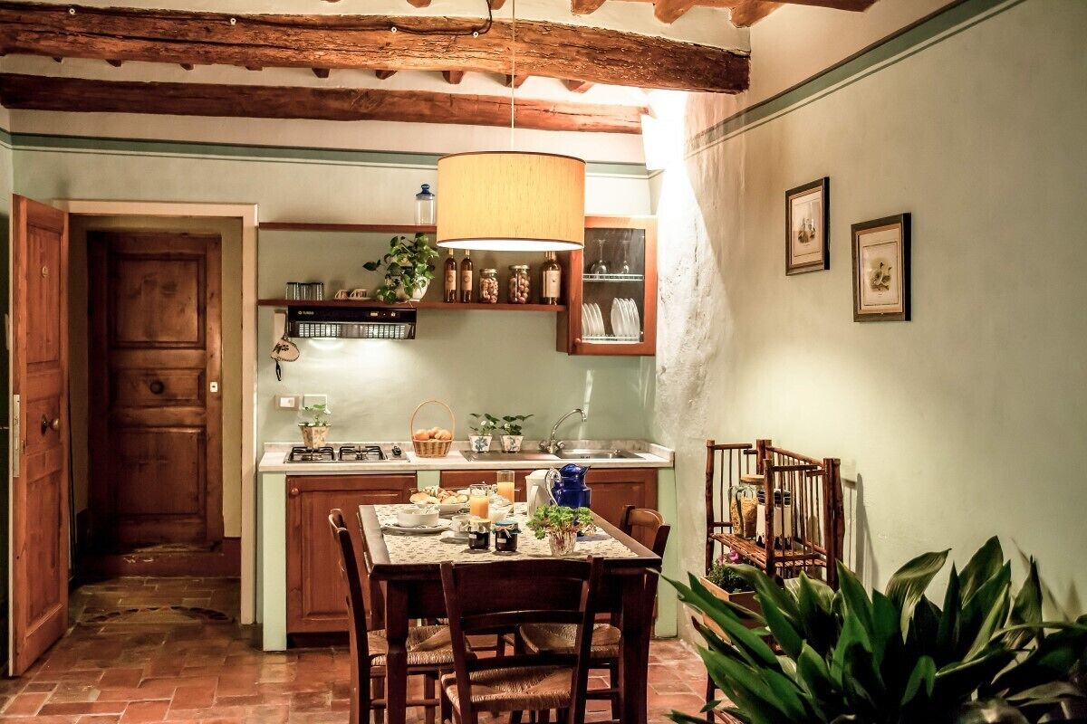 A cozy kitchen with wooden cabinets, a dining table set for four, and a hanging light fixture.