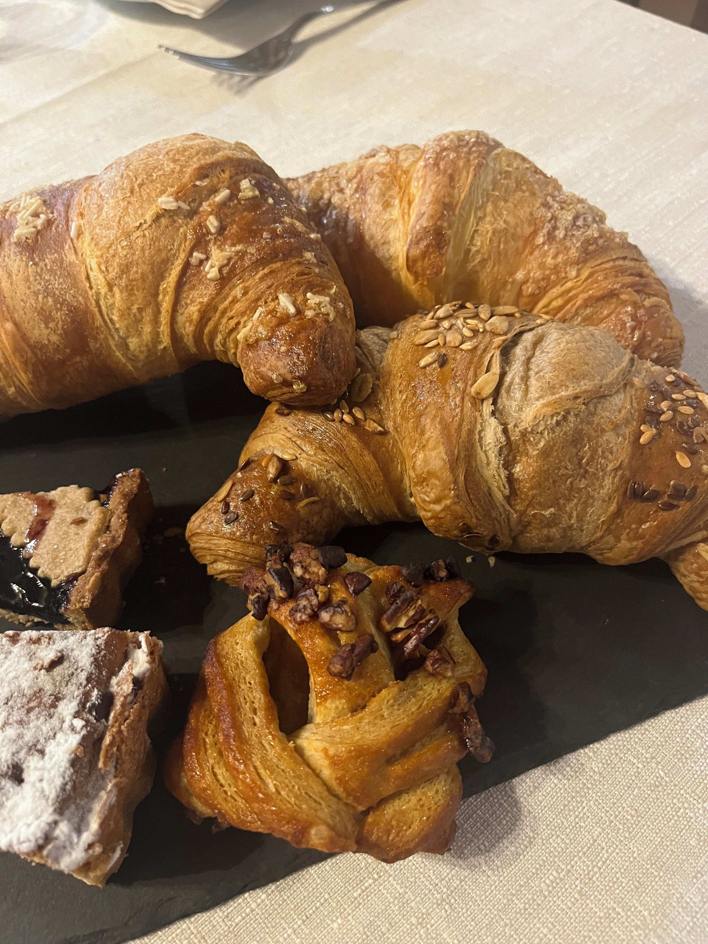 Verschiedene Backwaren, darunter Croissants und ein Dessert, auf einem Tisch.