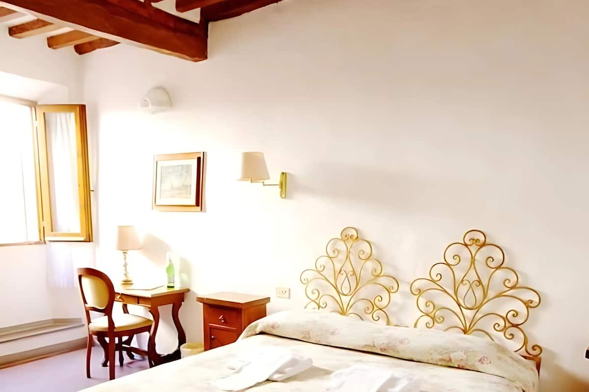 A bedroom with a bed, a desk, a chair, and a nightstand.