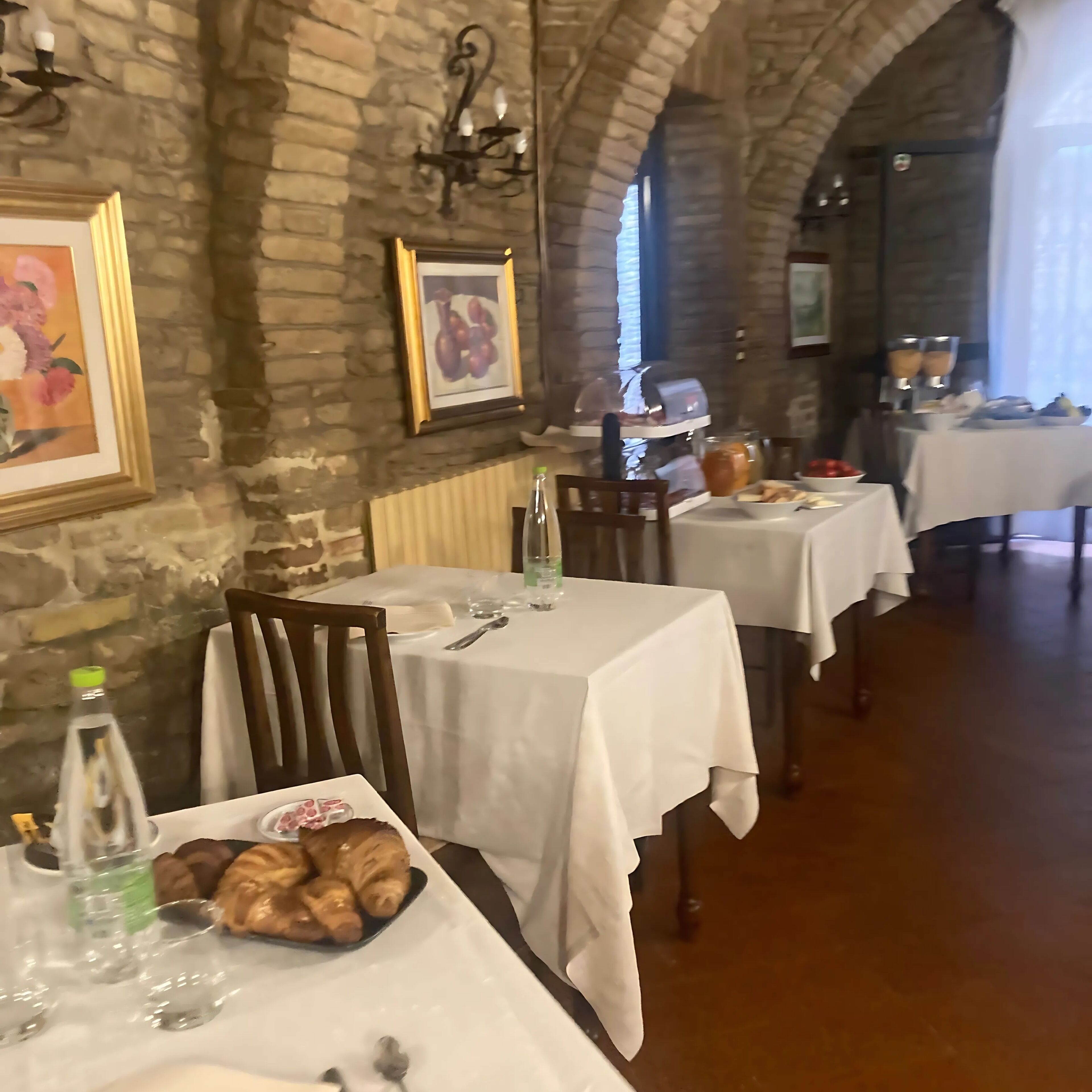 A restaurant with stone walls, white tablecloths, and rustic decor.