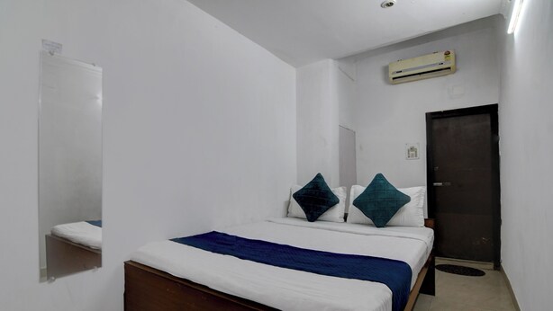 A bedroom with a bed, a mirror, a door, and an air conditioning unit. - Hotel Soft Petal (Bidhannagar)