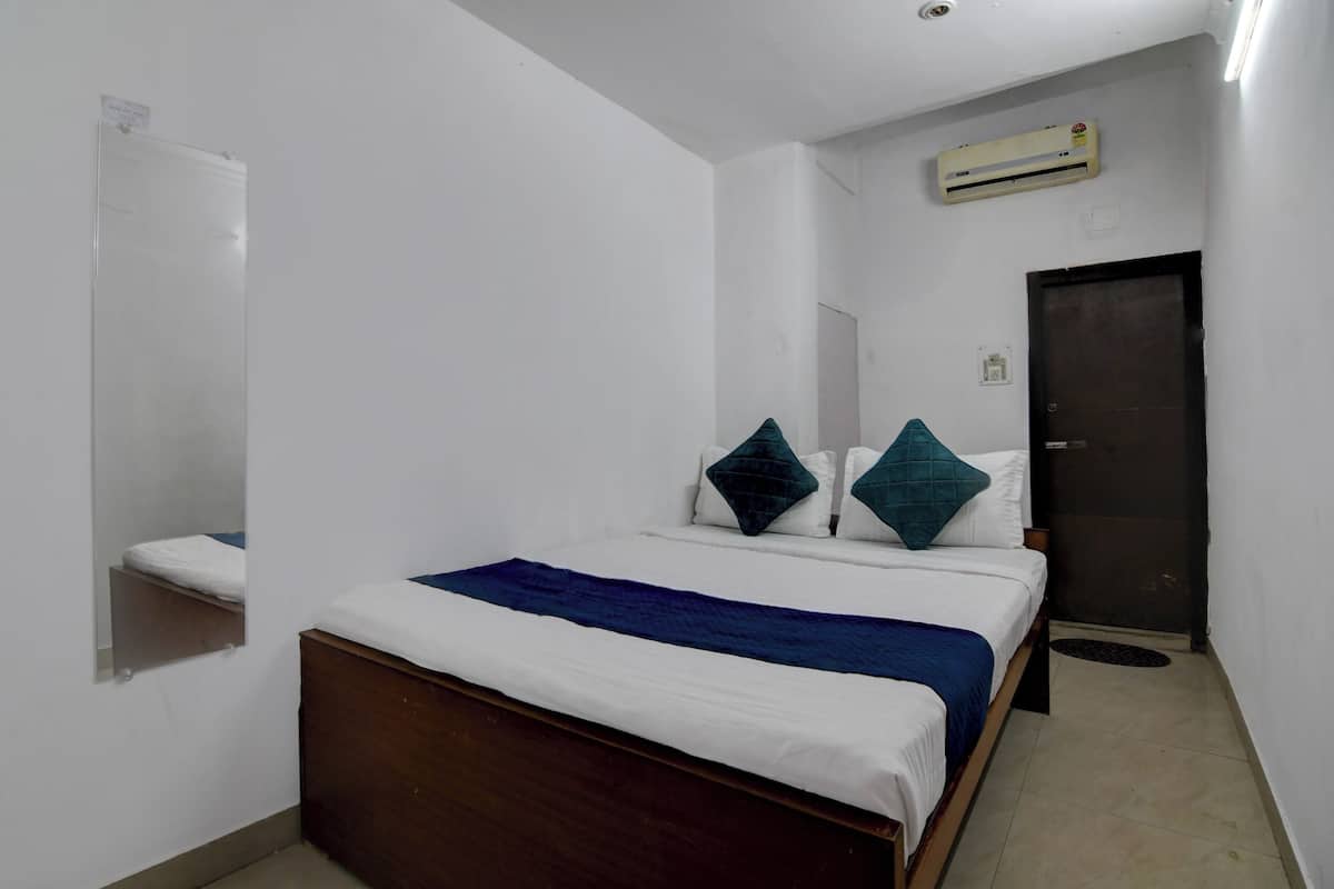 A bedroom with a bed, a mirror, a door, and an air conditioning unit.