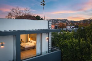 A modern two-story building with a balcony overlooking a cityscape.