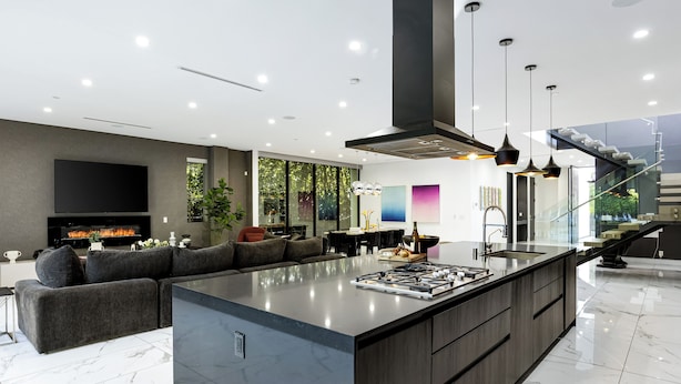 Una cucina moderna con una grande isola, forno integrato e zona pranzo con parete vetrata.