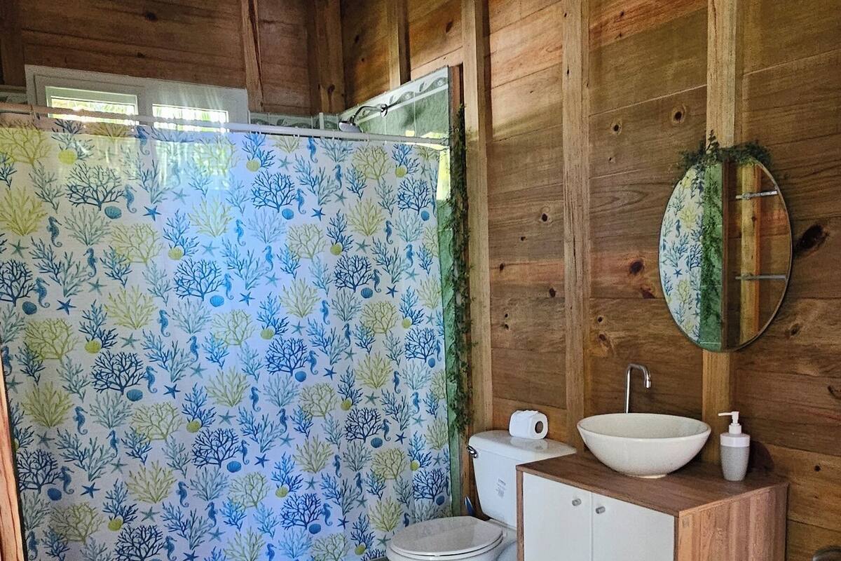 A wooden cabin bathroom with a toilet, sink, and mirror.