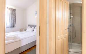 A hotel room with a bed, a nightstand, a shower, and a wooden wardrobe. - Awesome apartment in Veli Losinj with WiFi (Veli Losinj)