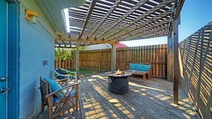 Un patio couvert avec un foyer, un espace salon et une terrasse en bois.