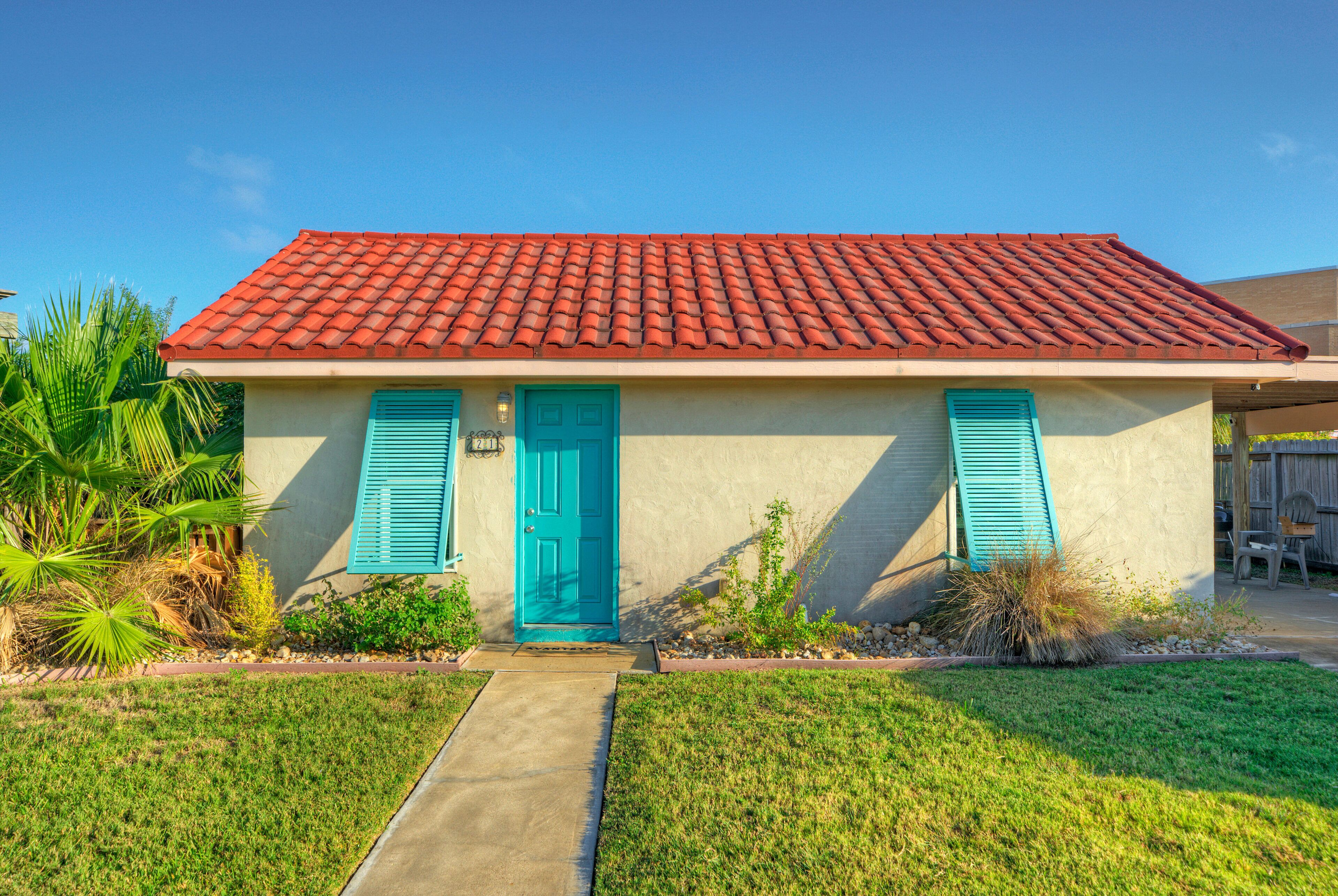 A single-story house with a red-tiled roof, a blue front door, and blue shutters.