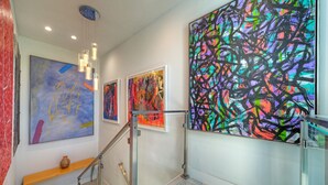 Ein Flur mit moderner Kunst an den Wänden, einer Holzbank und einem Glastrennzaun.