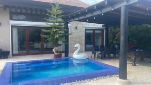 A swimming pool with a swan float, surrounded by outdoor furniture and a covered patio area. - 3-bedroom villa in tranquil Cap Cana Punta Cana with AC (Cap cana punta cana)