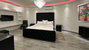 A modern bedroom with a large bed, a TV mounted on the wall, a chandelier, and a painting. - 3-bedroom villa in tranquil Cap Cana Punta Cana with AC (Cap cana punta cana)