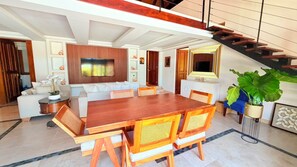 Ein modernes Wohnzimmer mit einem Holzesstisch, weißen Sofas und einer Treppe.