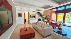 Ein modernes Wohnzimmer mit Sofa, Couchtisch und einer Treppe, die auf einen Balkon mit Blick führt.