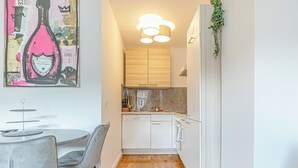 Une cuisine compacte dotée de meubles en bois, d’un pare-feu en marbre et d’un coin repas avec une table ronde et des chaises.