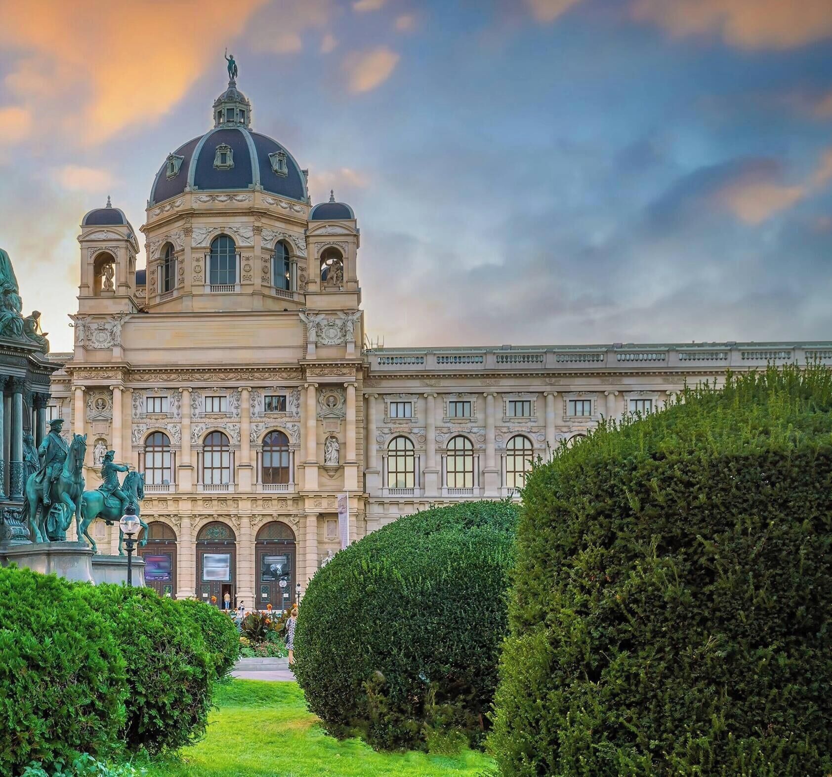 Ein prachtvolles Gebäude mit einer großen Kuppel und klassischer Architektur, umgeben von gepflegten Hecken und Statuen.