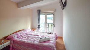 Una camera da letto con un letto, un comodino, una finestra con tende e un balcone.