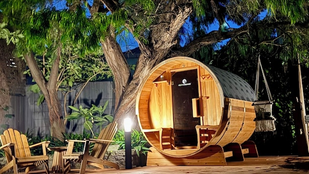 A wooden cabin with a circular entrance, a small table, and two chairs outside. - Elwood Retreat - Sauna, 4 bedrooms, large garden, close to shops, cafe, train (Elwood)